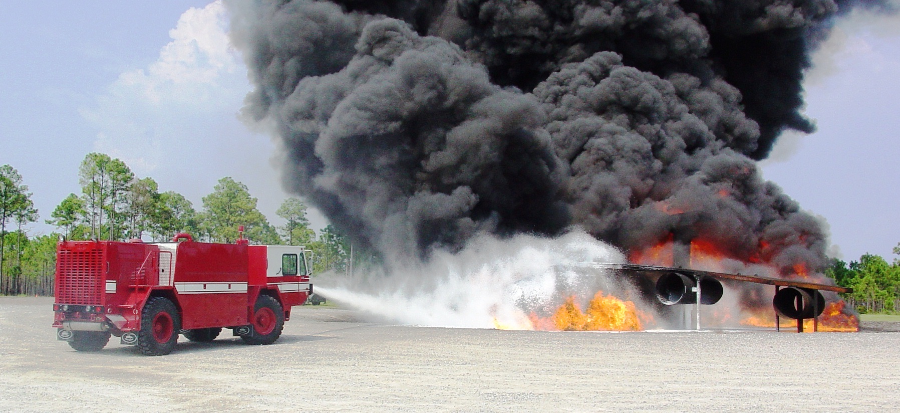 Firefighting vehicle putting out a fire at an aircraft firefighter training site